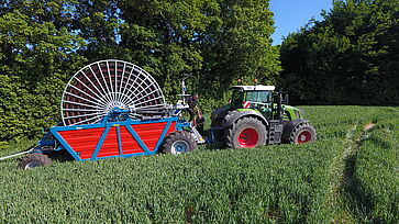 Fasterholt vandingsmaskine trukket af en Fendt traktor på grøn beplantet mark