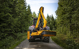 Valtra traktor kører på grusvej med Kronos Extendo 610 klippearm monteret bagpå
